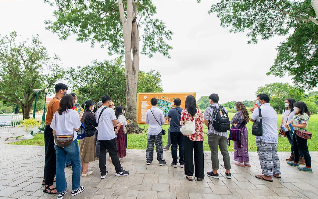 Tour group with guide viewing map during Ayutthaya temples visit.