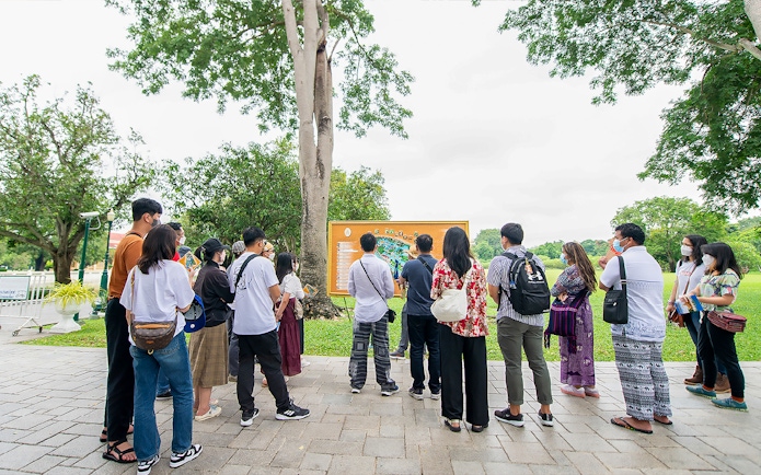 Tour group with guide viewing map during Ayutthaya temples visit.