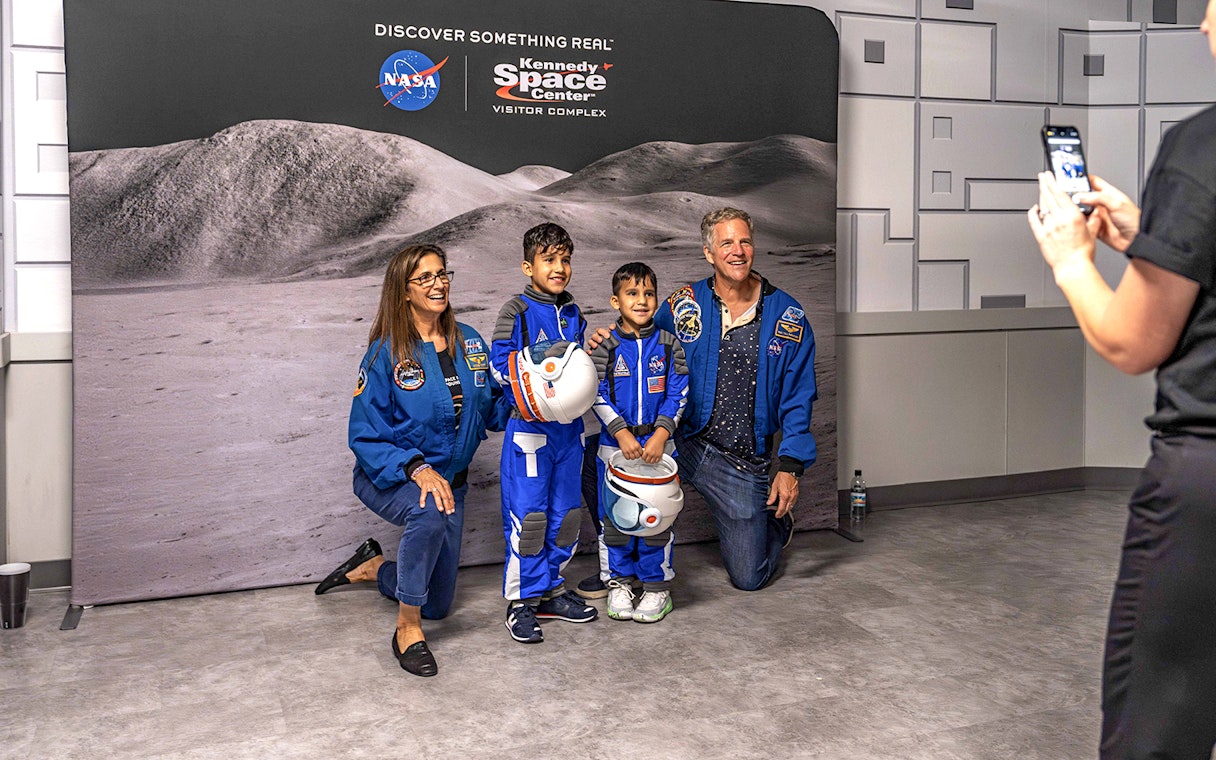 Visitors in astronaut suits pose at Kennedy Space Center's after-hours event.