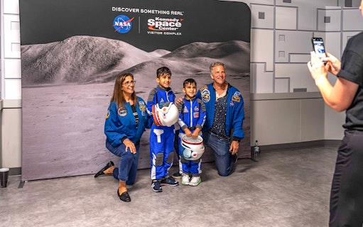 Visitors in astronaut suits pose at Kennedy Space Center's after-hours event.