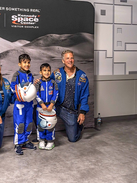 Visitors in astronaut suits pose at Kennedy Space Center's after-hours event.
