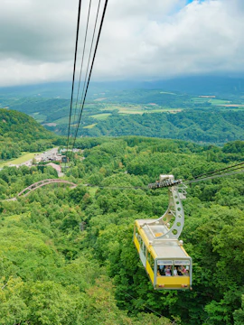 Mt. Usu cable car ascending over lush green landscape in Hokkaido, Japan.