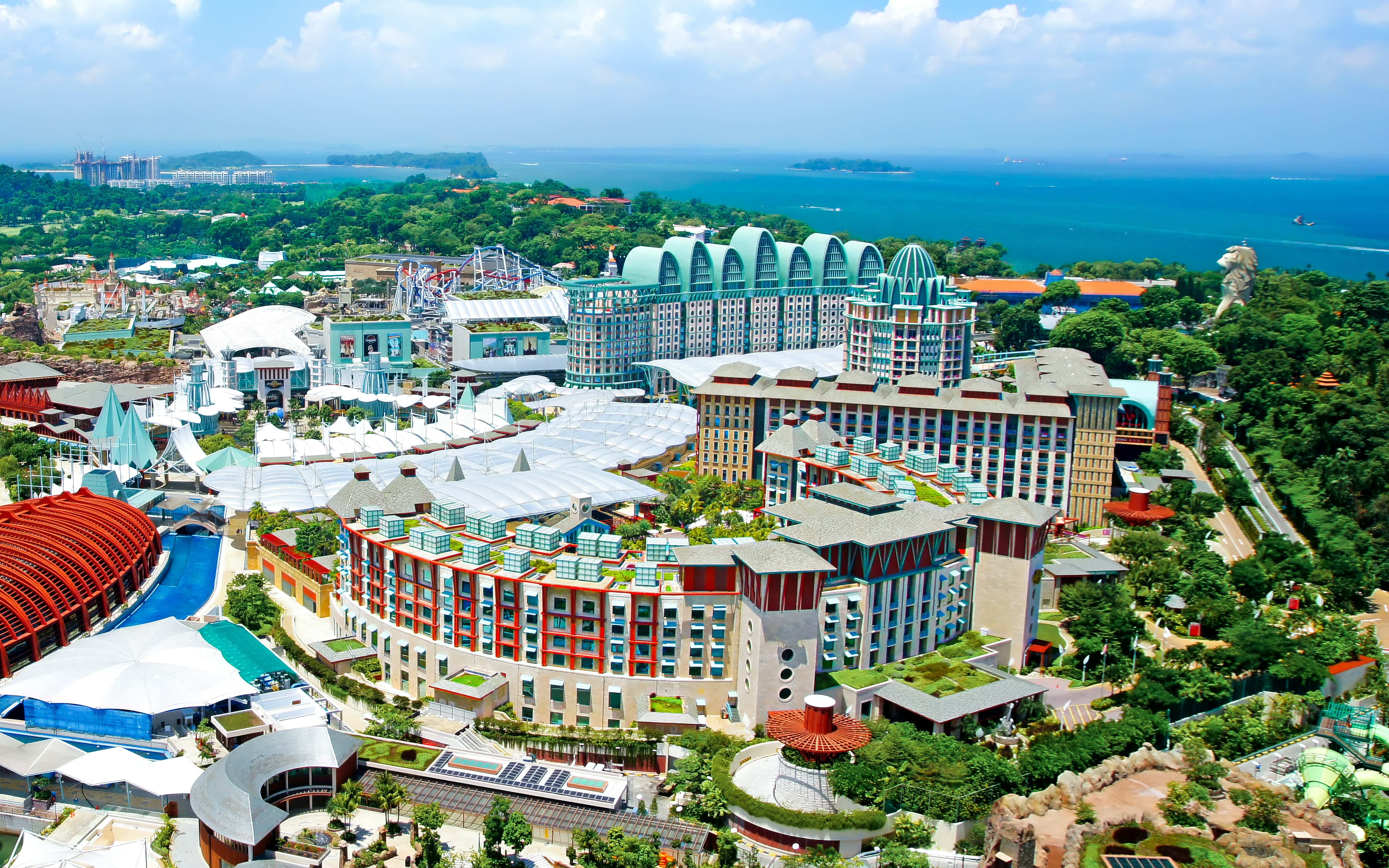 Aerial view of Sentosa Island's Resorts World complex with lush greenery and ocean backdrop.