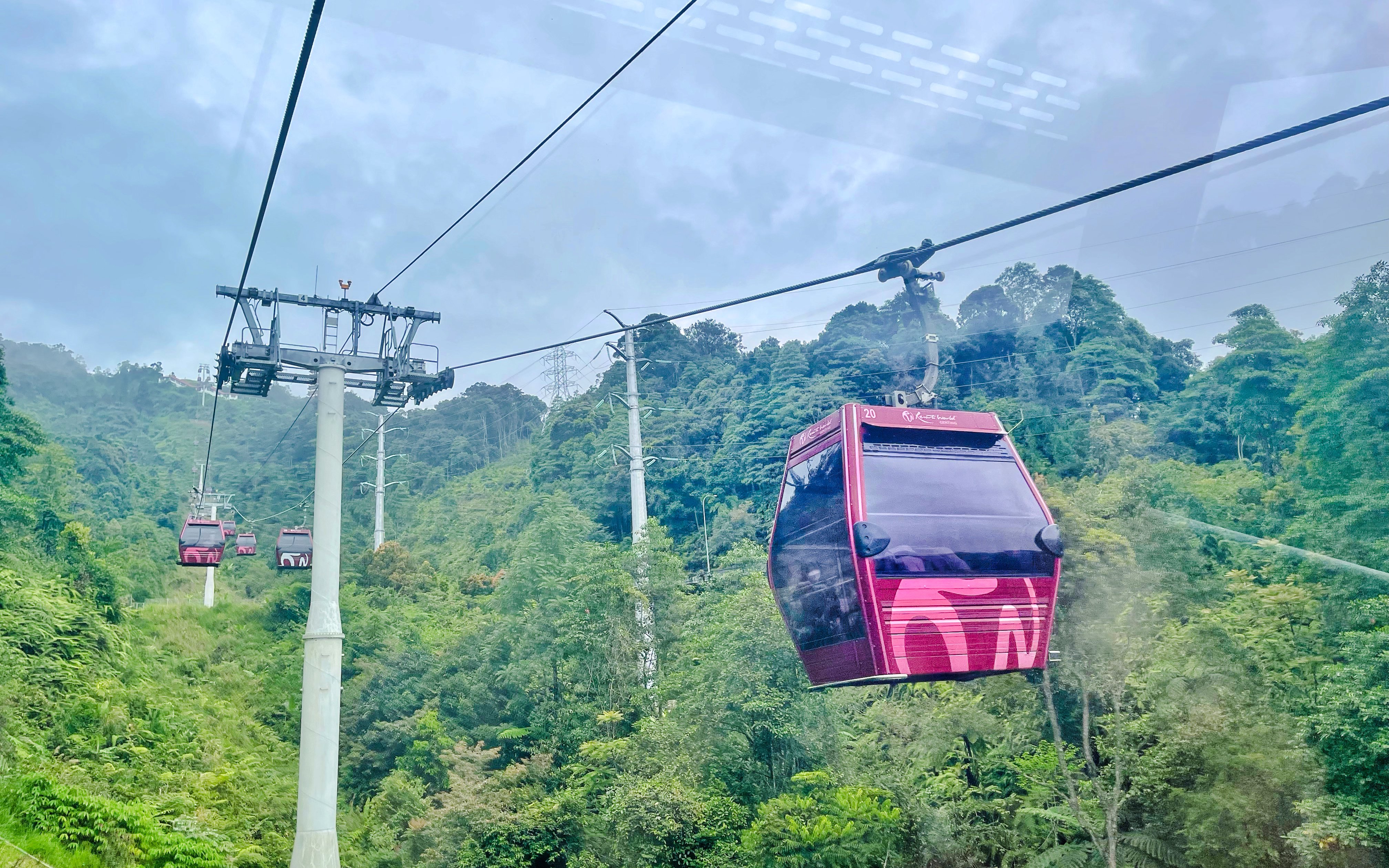 Cable car ascending through lush greenery at Genting Highlands Premium Outlets.