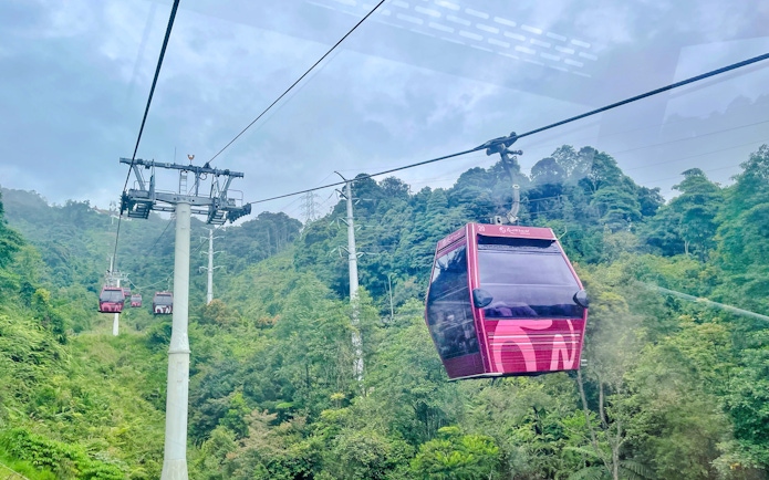 Cable car ascending through lush greenery at Genting Highlands Premium Outlets.