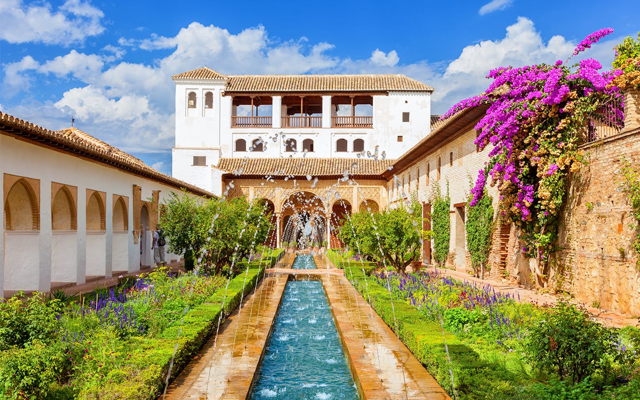 Alhambra's Generalife gardens with fountains and vibrant flowers in Granada, Spain.