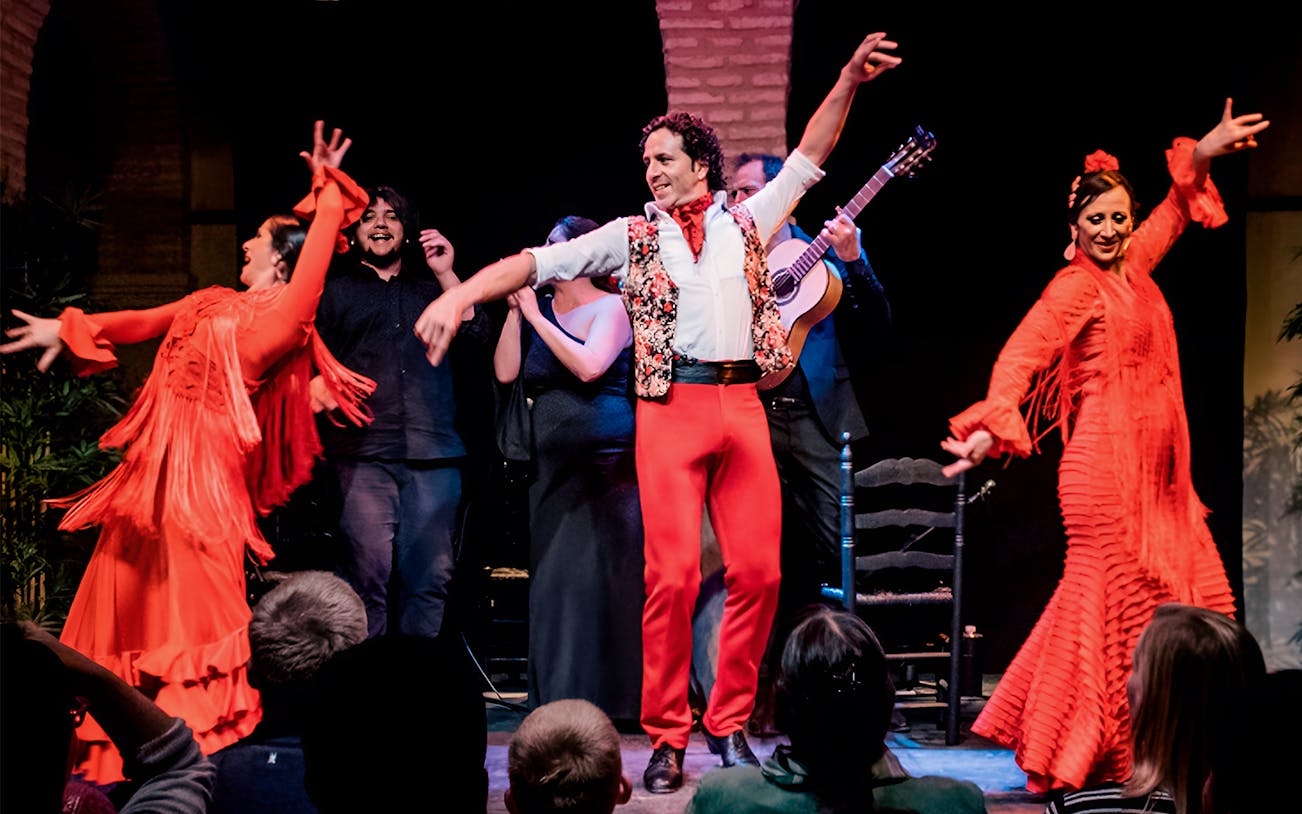 Flamenco dancers performing in Triana, Seville with musicians in the background.