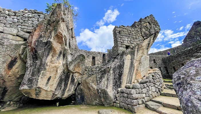 Temple of the Condor stone structure at Machu Picchu with blue sky background.