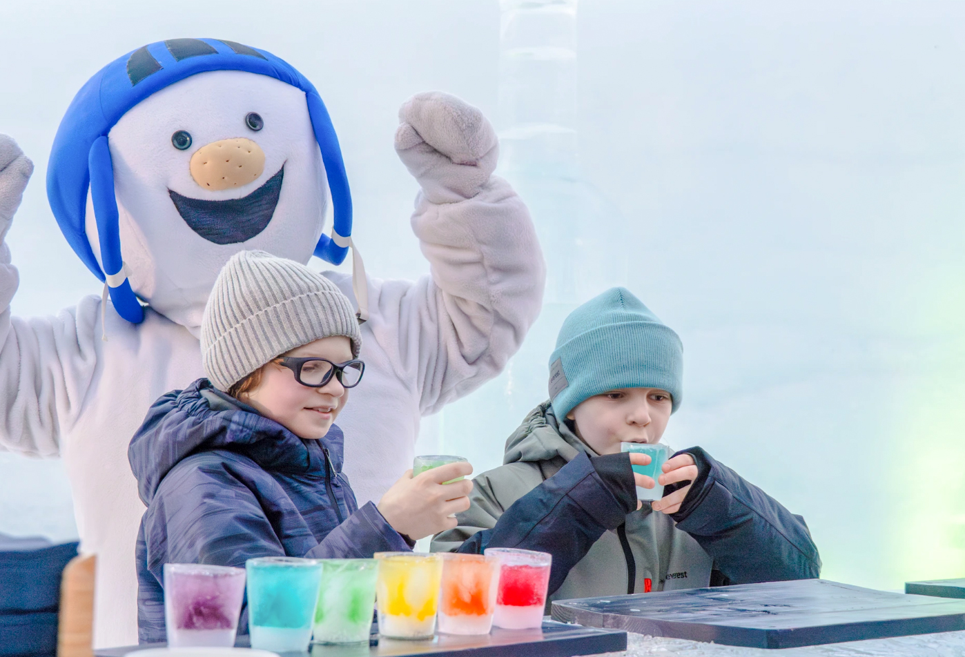 Children enjoying colorful drinks with a snowman character at Snowman World, Santa Claus Village.