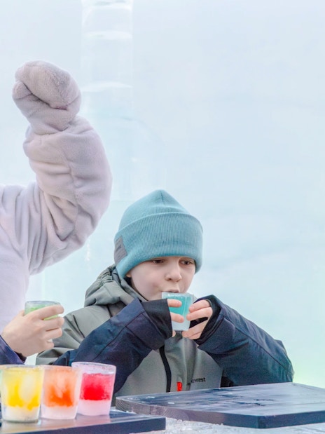 Children enjoying colorful drinks with a snowman character at Snowman World, Santa Claus Village.
