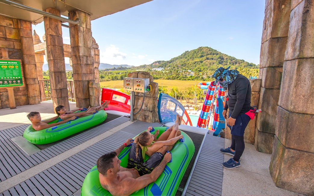 Visitors on inflatable rafts at Andamanda Phuket water slide with scenic mountain view.