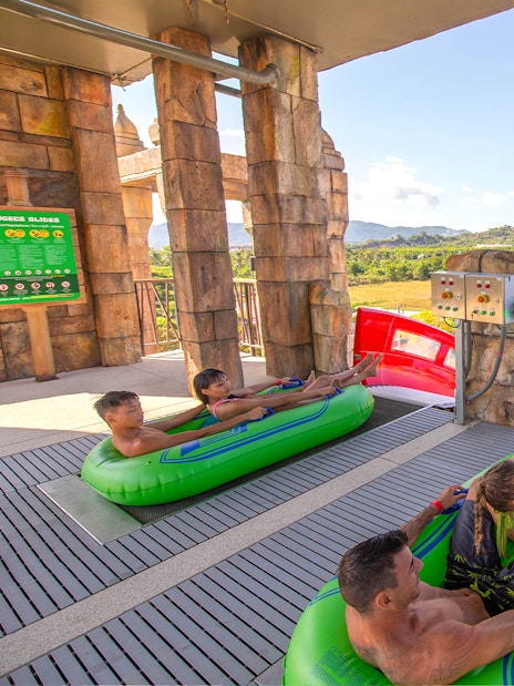 Visitors on inflatable rafts at Andamanda Phuket water slide with scenic mountain view.