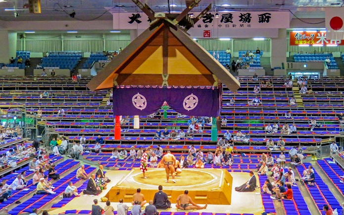 Sumo wrestlers competing in a Fukuoka arena during a tournament.