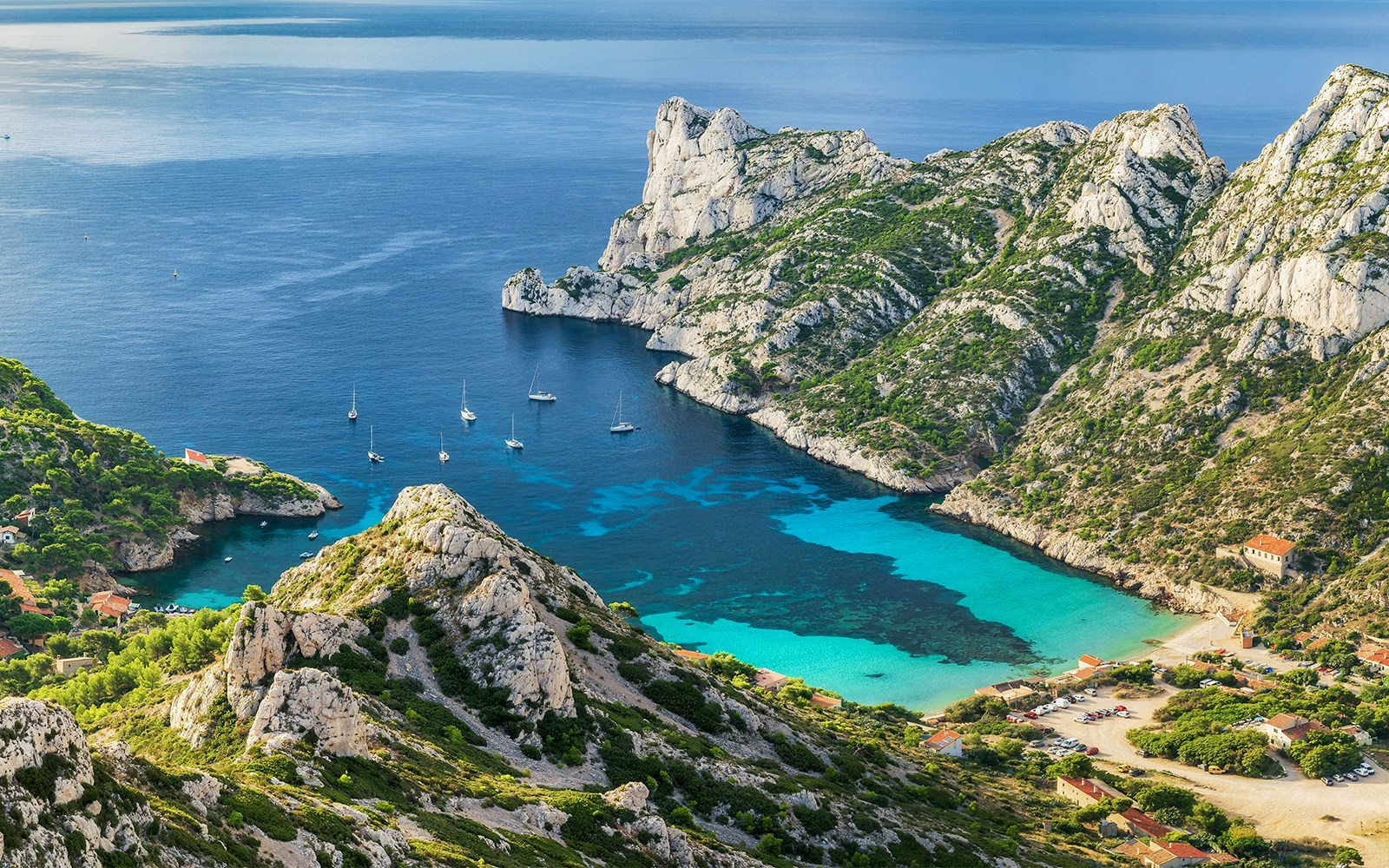 Sailboats in a turquoise bay surrounded by rocky cliffs at Calanques National Park, France.