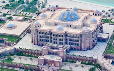 Aerial view of Emirates Palace in Abu Dhabi, showcasing its grand architecture and blue domes.