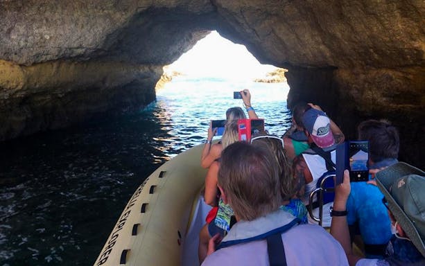 Boat entering Benagil Cave on Algarve tour from Portimão, passengers taking photos.