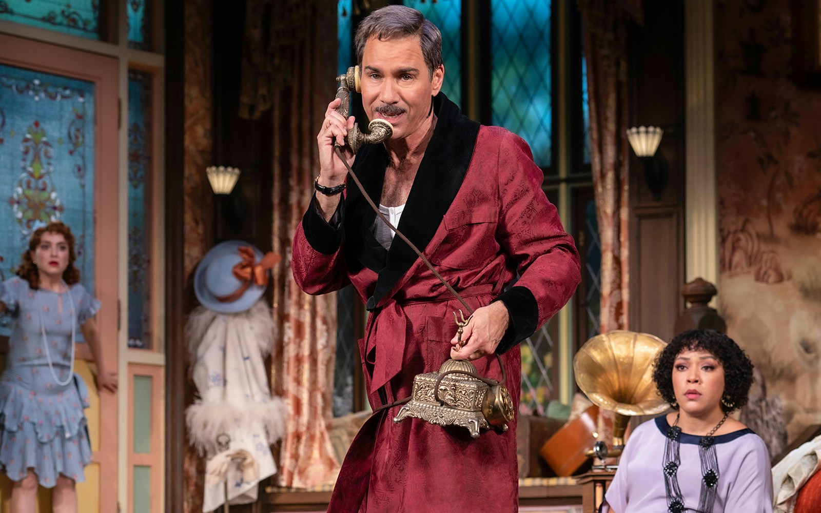 Man in a red robe using a vintage phone in a room at The Cottage.