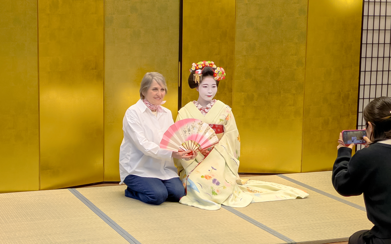 Woman with Maiko holding a fan, photographer capturing the moment in Kyoto.