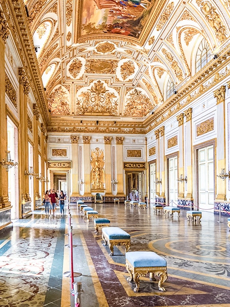 Royal Palace of Caserta interior with ornate ceiling and gilded walls.