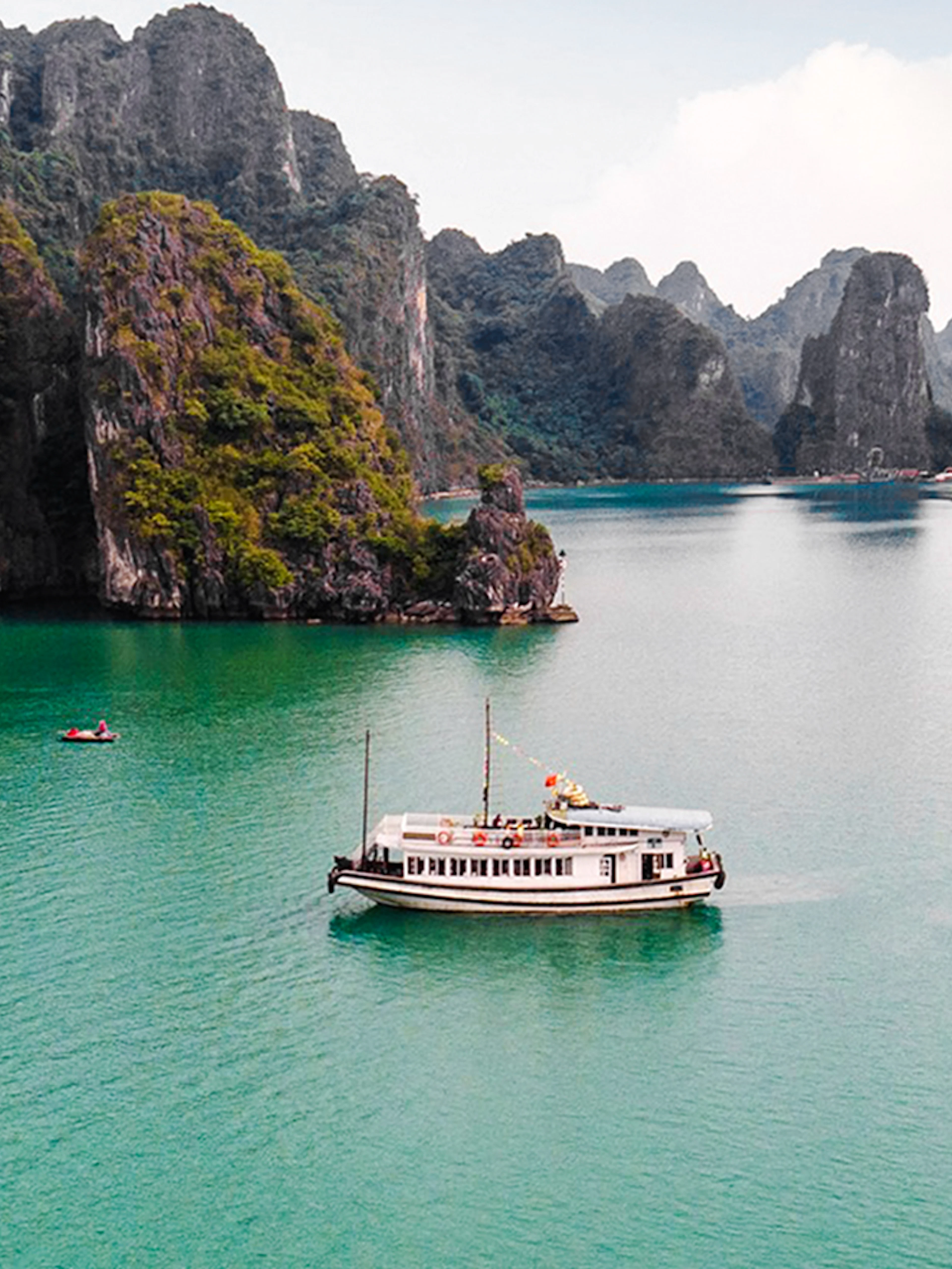 Cruise ship on Ha Long Bay's emerald waters with limestone islands.