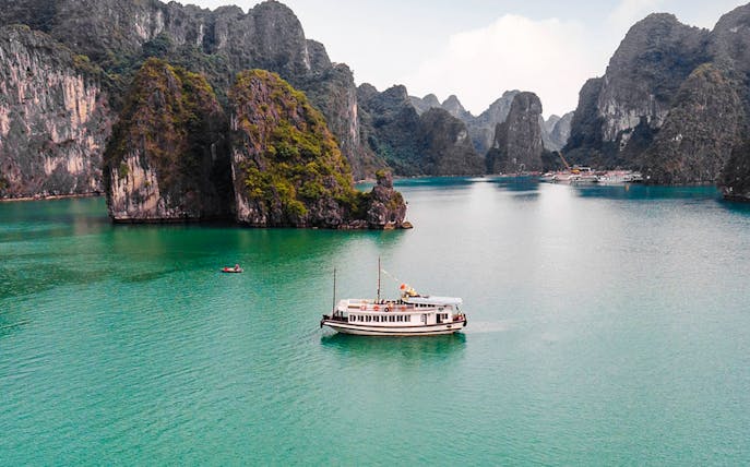 Cruise ship on Ha Long Bay's emerald waters with limestone islands.