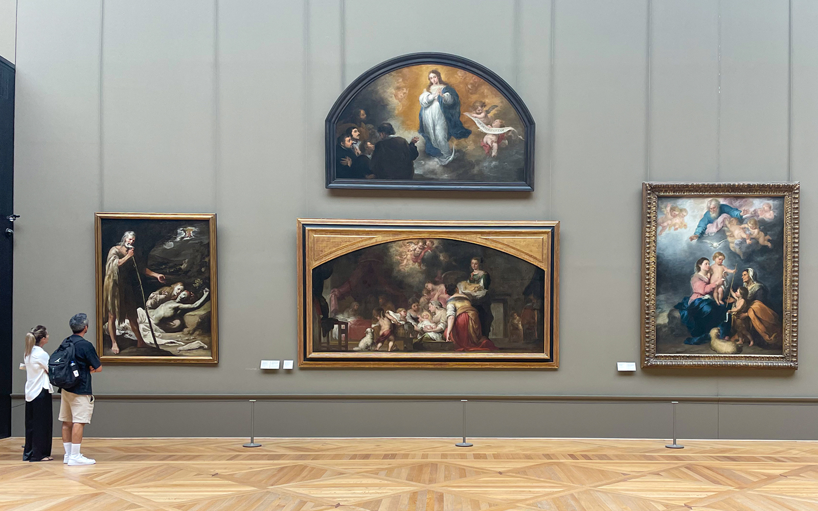 Louvre Museum visitors viewing religious paintings in a gallery.