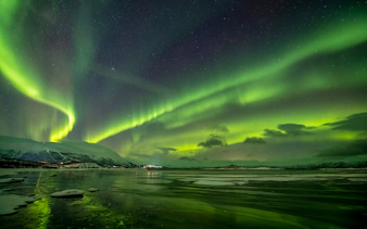 Northern lights over snowy landscape in Abisko, Sweden.