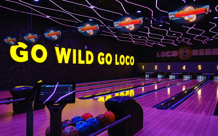 Bowling lanes at Loco Bear, Dubai with neon lights and bowling balls.