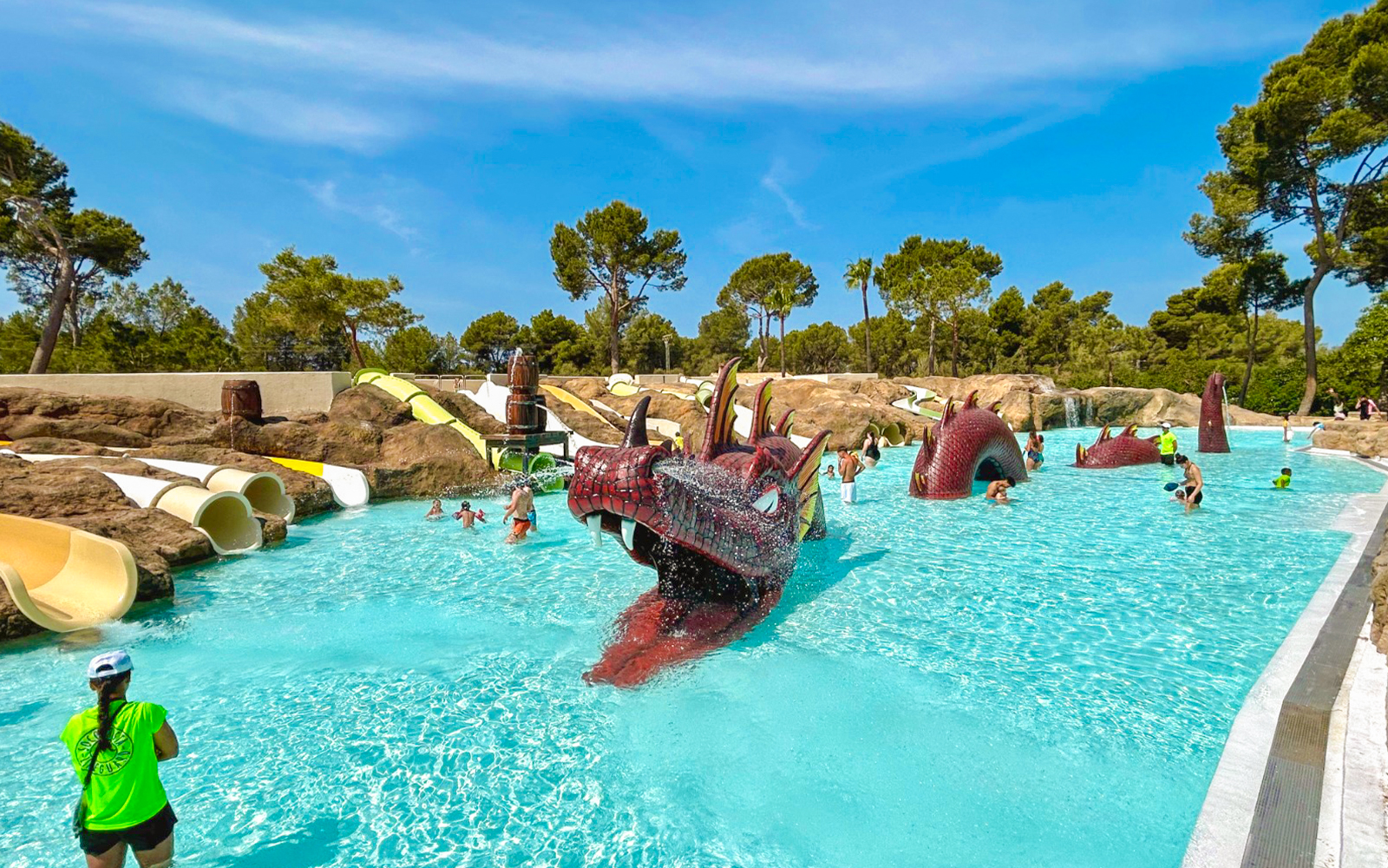 Visitors enjoying the dragon-themed pool at Aqualand El Arenal with slides and water features.