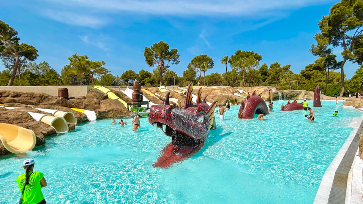 Visitors enjoying the dragon-themed pool at Aqualand El Arenal with slides and water features.