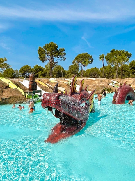 Visitors enjoying the dragon-themed pool at Aqualand El Arenal with slides and water features.