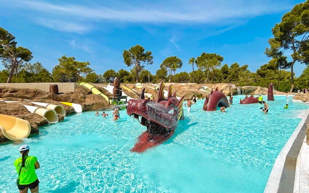 Visitors enjoying the dragon-themed pool at Aqualand El Arenal with slides and water features.
