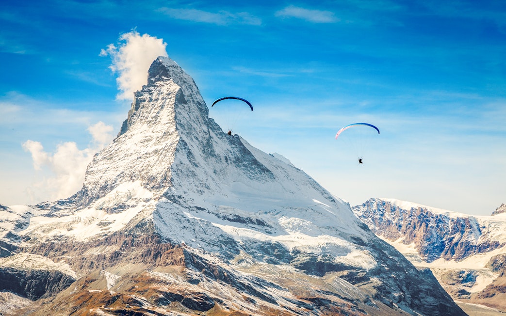 Paragliders soaring near Matterhorn mountain with guide in Switzerland.