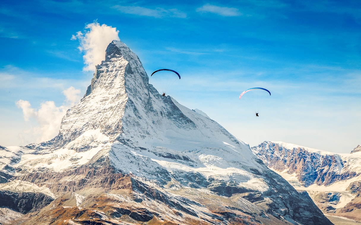 Paragliders soaring near Matterhorn mountain with guide in Switzerland.