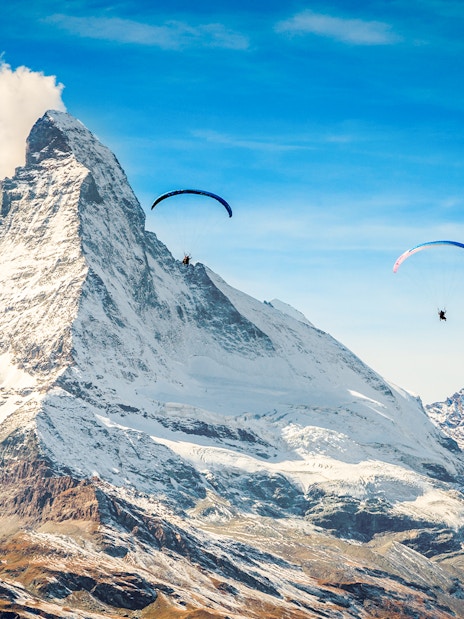 Paragliders soaring near Matterhorn mountain with guide in Switzerland.