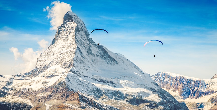Paragliders soaring near Matterhorn mountain with guide in Switzerland.
