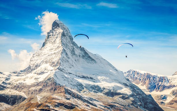 Paragliders soaring near Matterhorn mountain with guide in Switzerland.