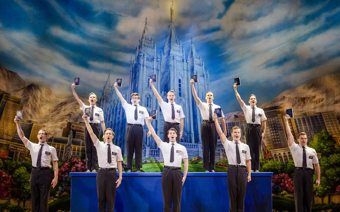 Cast performing The Book of Mormon on stage in Brisbane, with a backdrop of a temple.
