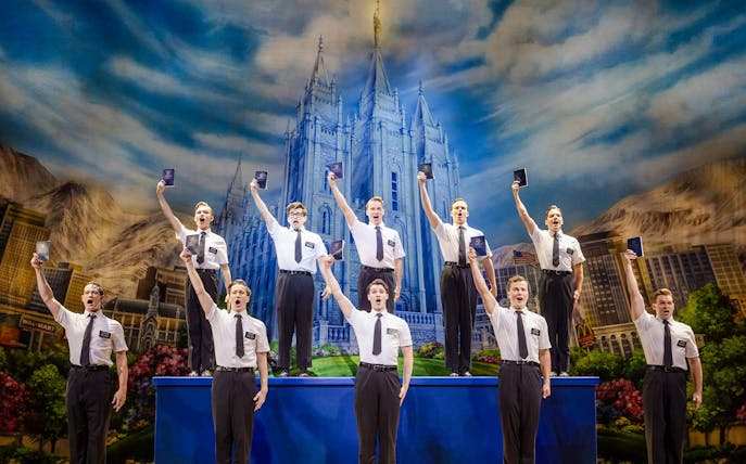 Cast performing The Book of Mormon on stage in Brisbane, with a backdrop of a temple.