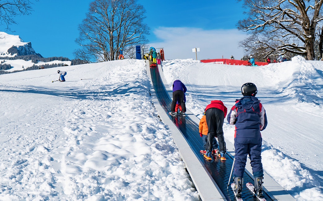 Children on a ski conveyor belt in Grindelwald during a beginner snowboard package from Interlaken.