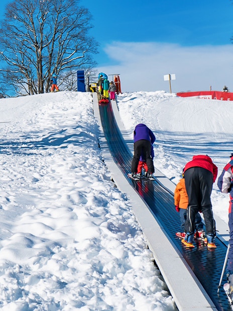 Children on a ski conveyor belt in Grindelwald during a beginner snowboard package from Interlaken.
