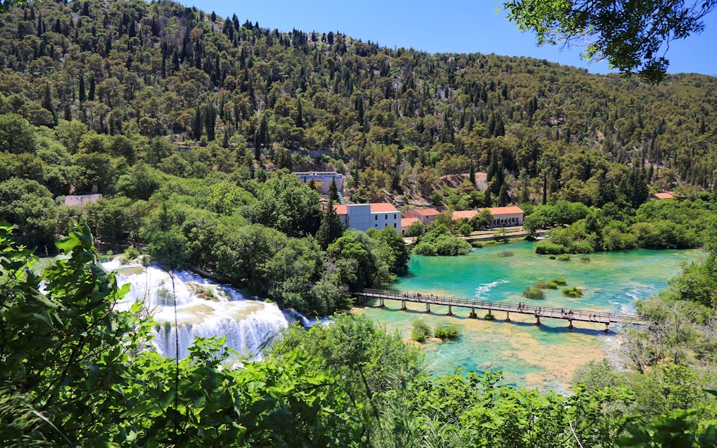 Bridge over turquoise water leading to Krka waterfall at Krka National Park, Croatia.