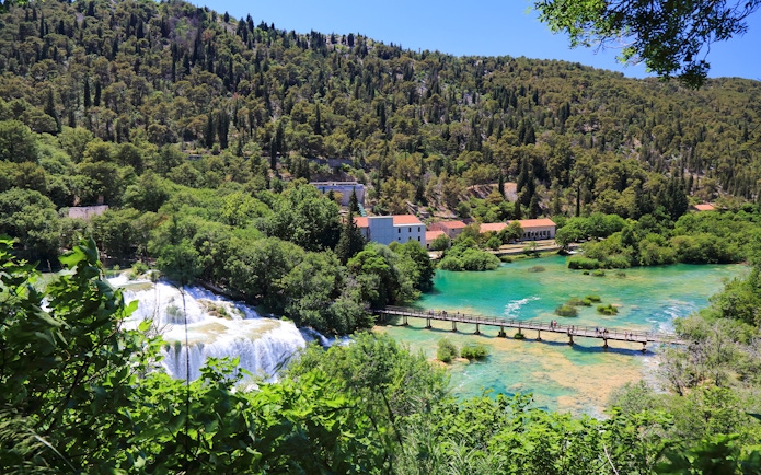 Bridge over turquoise water leading to Krka waterfall at Krka National Park, Croatia.