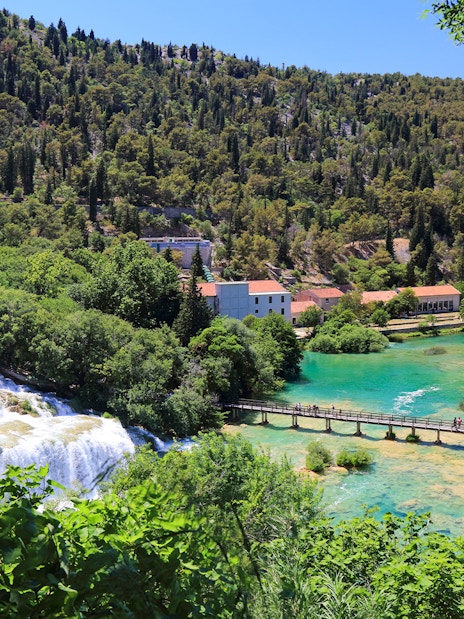 Bridge over turquoise water leading to Krka waterfall at Krka National Park, Croatia.