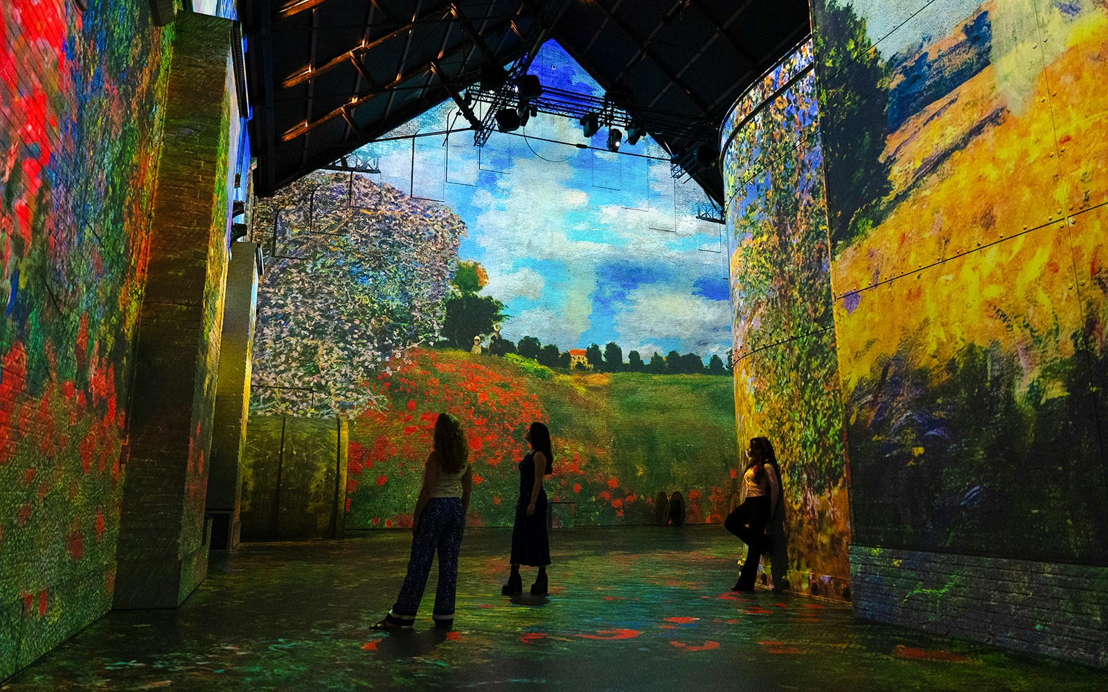 Monet's landscapes projected at Fabrique des Lumières exhibition, visitors observing.