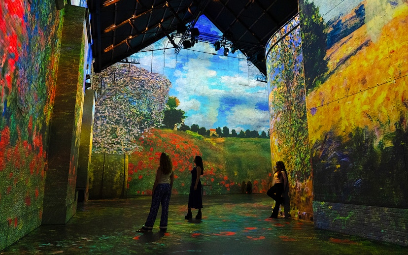 Monet's landscapes projected at Fabrique des Lumières exhibition, visitors observing.