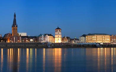 Duesseldorf skyline at dusk with illuminated buildings along the Rhine River during Panorama City Cruise.