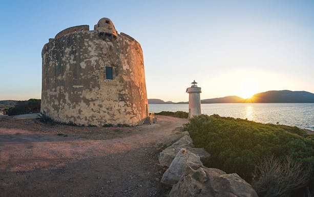 Ancient watchtower and lighthouse at sunset in Porto Conte, Sardinia.