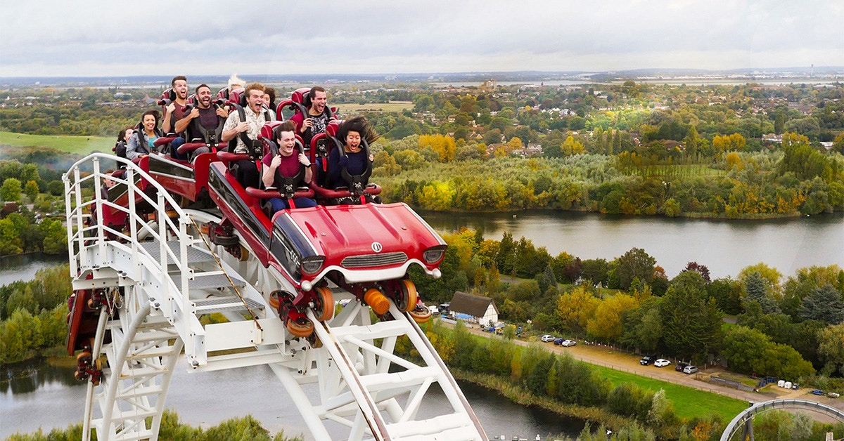 Roller coaster descending at Thorpe Park with riders enjoying the view of surrounding landscape.