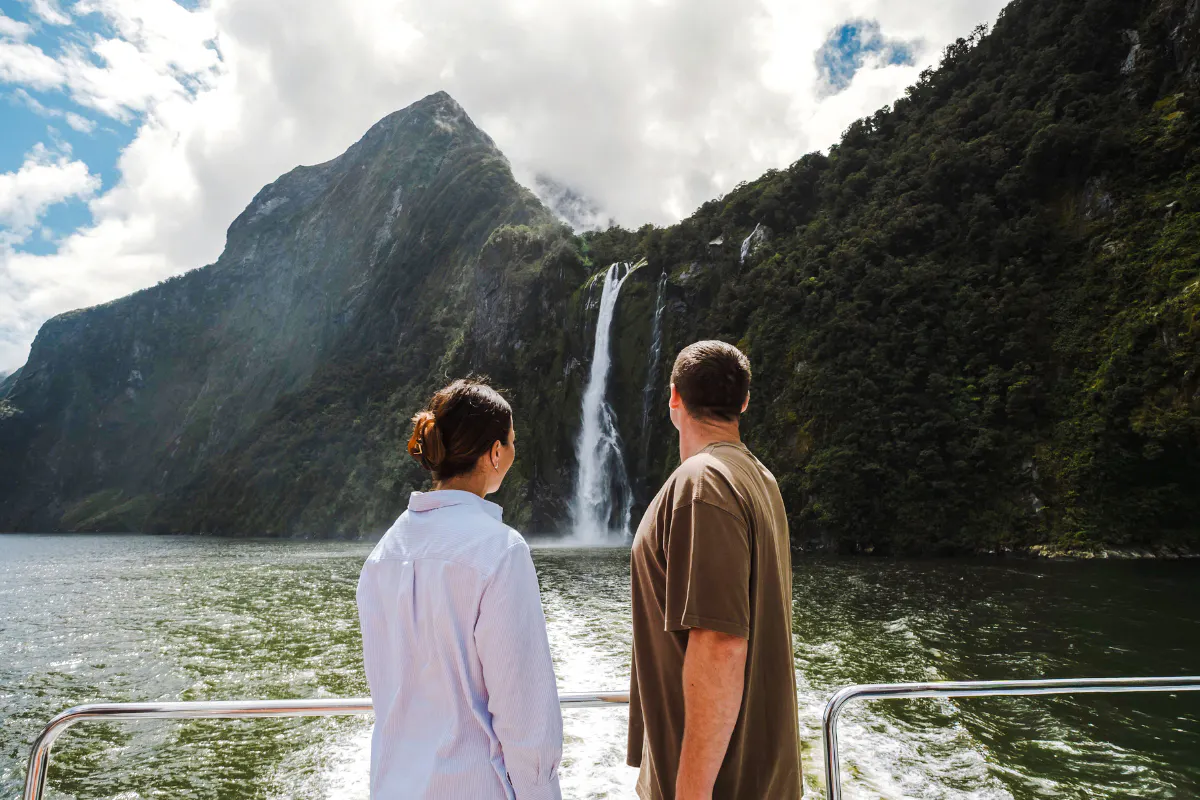 Couple on Milford Sound cruise viewing waterfall, part of Te Anau small group tour.